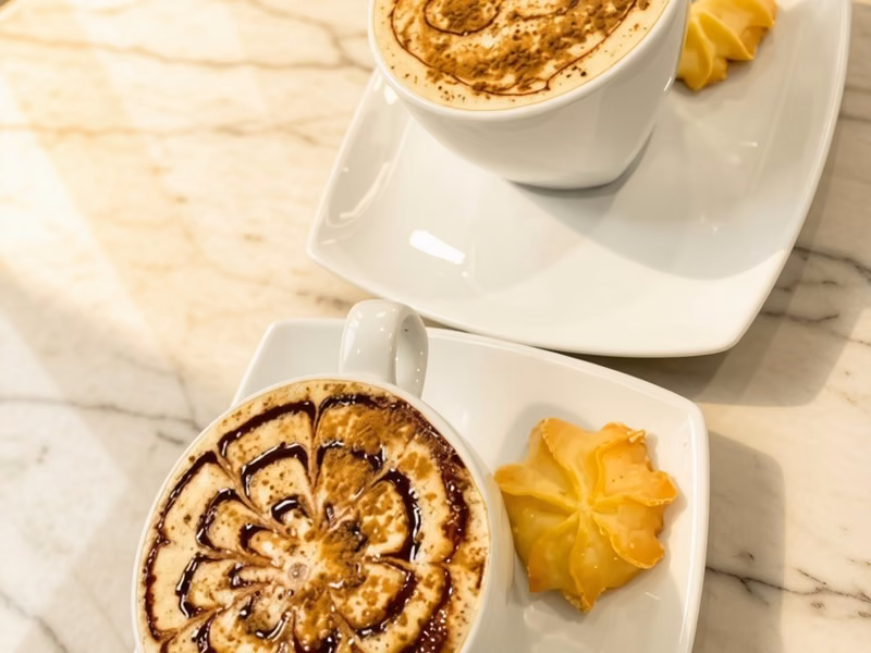 Capuchinos con arte latte y galletas en el salón de onces de Pastelería Dulcita, Bogotá