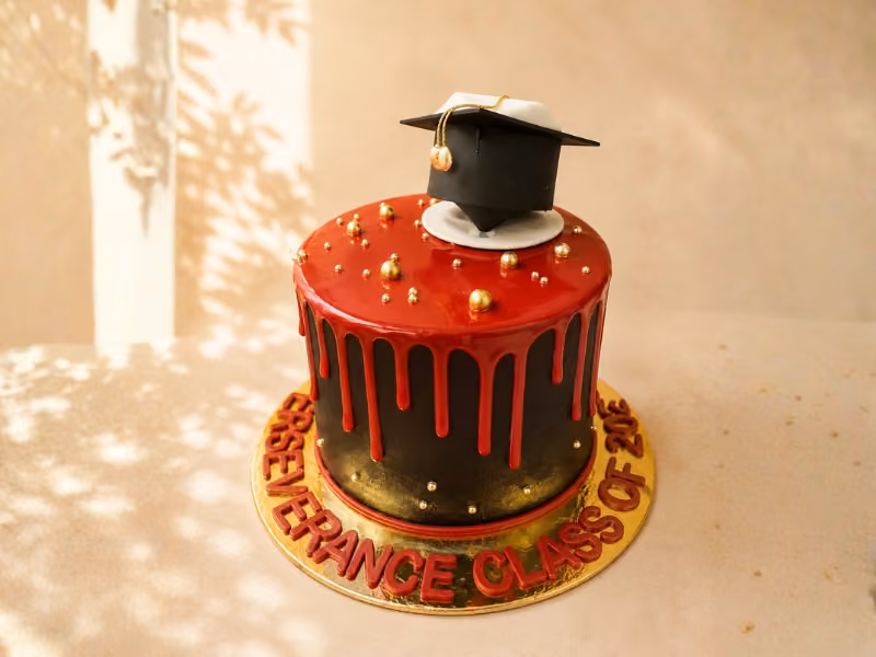 Torta de grados roja con efecto drip dorado y birrete, elaborada por Pastelería Dulcita en Bogotá